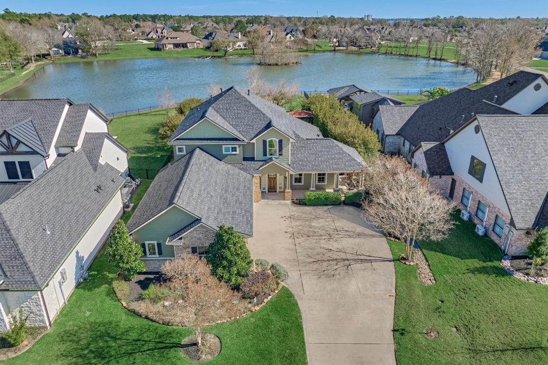 | the mckellar group Drone Shot of a Large Lake House with Waterfront Scenery Behind It