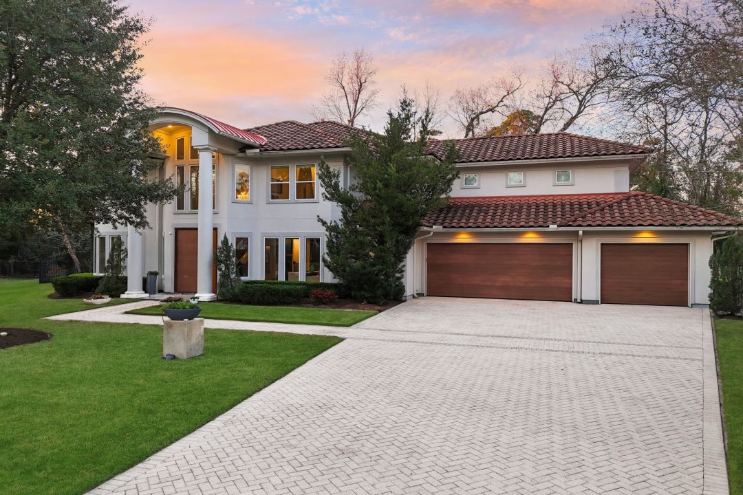 | the mckellar group Exterior View of a High End Home from the End of the Driveway the Home is White with Brown Accented Roof Front Door and Garage Doors