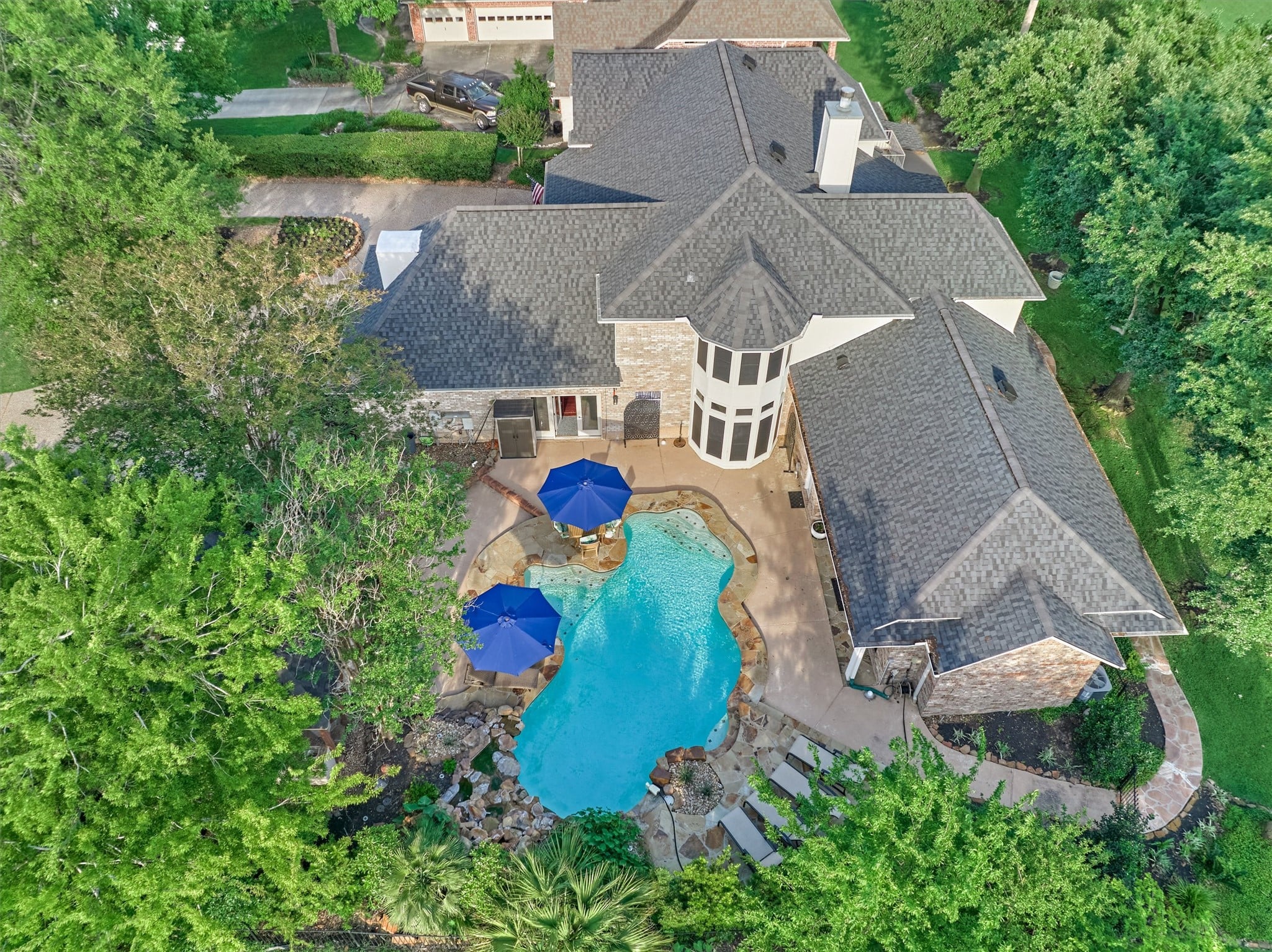 | the mckellar group Aerial View of a Large House with Multiple Gray Shingled Roofs a Kidney shaped Blue Pool and Surrounding Green Trees