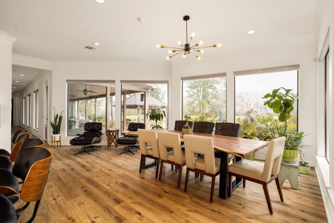 Bright Conference Room with a Long Wooden Table Beige Chairs and Large Windows Overlooking Greenery Indoors Filled with Plants