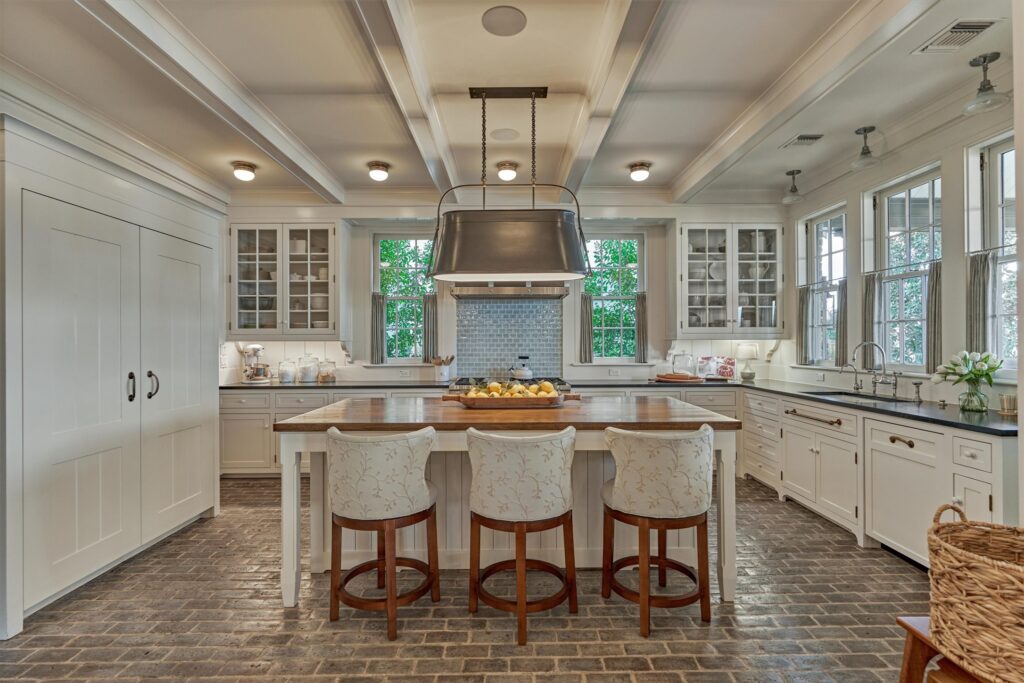 130 020 100 bentwater bay dr | the mckellar group Bright White Kitchen with a Large Central Island and Three Upholstered Stools Pendant Lighting and a Stainless Vent Hood Above the Stove Area
