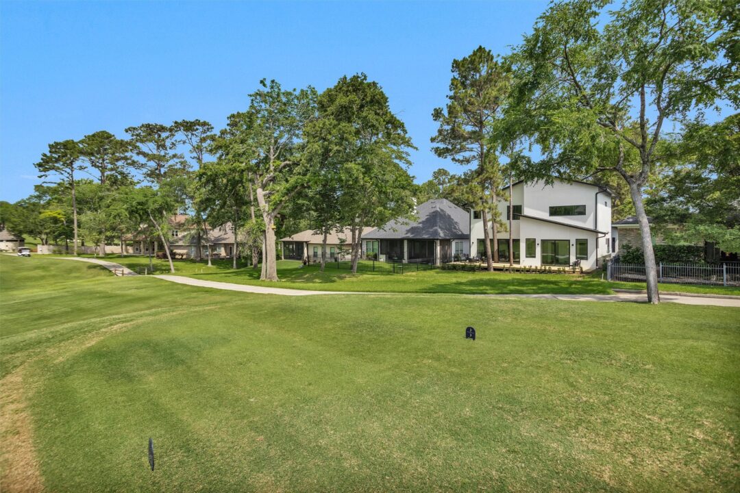 | the mckellar group Sunny Suburban Scene with a Modern White House Lush Green Lawn and Tall Mature Trees Under a Clear Blue Sky