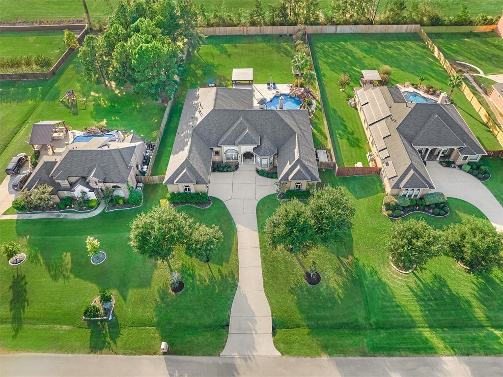 18823 quiet water way luxury home for sale in montgomery | the mckellar group Aerial View of Three Suburban Houses with Manicured Lawns Curved Driveways and Backyard Pools Visible Behind Each Home