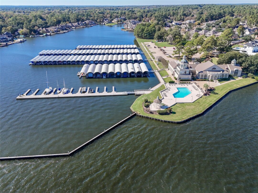Aerial View of a Marina with Long Rows of Covered Boat Slips Along the Shoreline and Nearby Clubhouse with a Pool