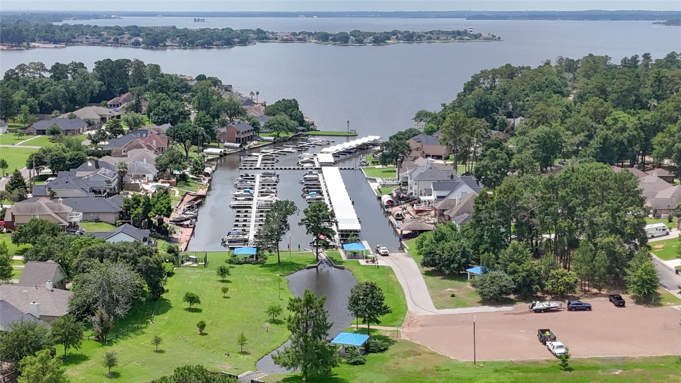 | the mckellar group Aerial View of a Canal Marina Lined with Boats Neighboring Houses and Green Yards Along Tree filled Shores by a Large Lake