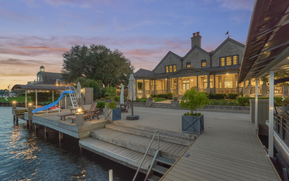 | the mckellar group Lakeside Resort Building at Sunset with a Wooden Dock Lounge Chairs and a Blue Waterslide by the Water