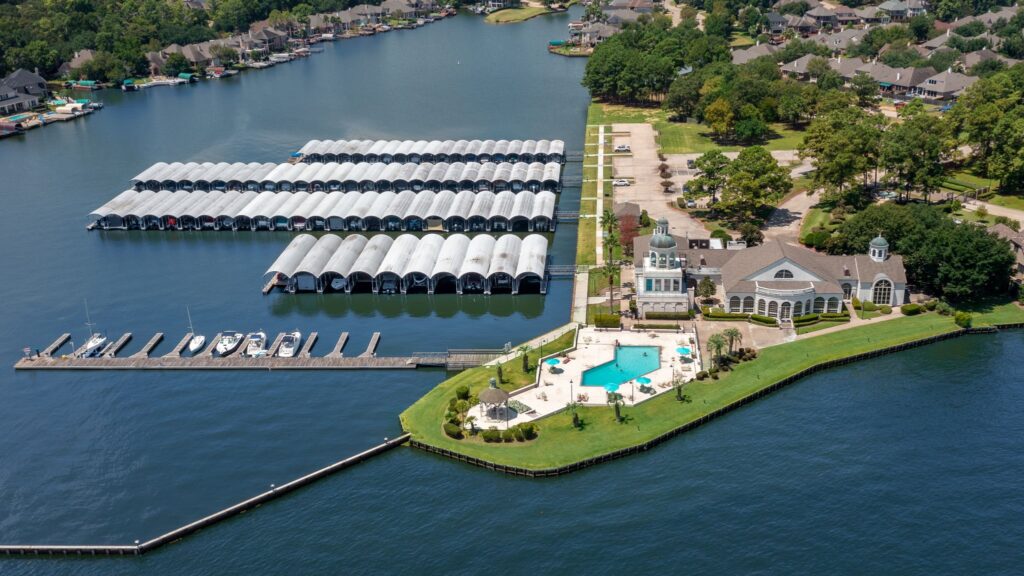 Aerial View of a Lakeside Marina with Many Rows of Covered Boat Slips a Clubhouse and a Swimming Pool on a Green Lawn