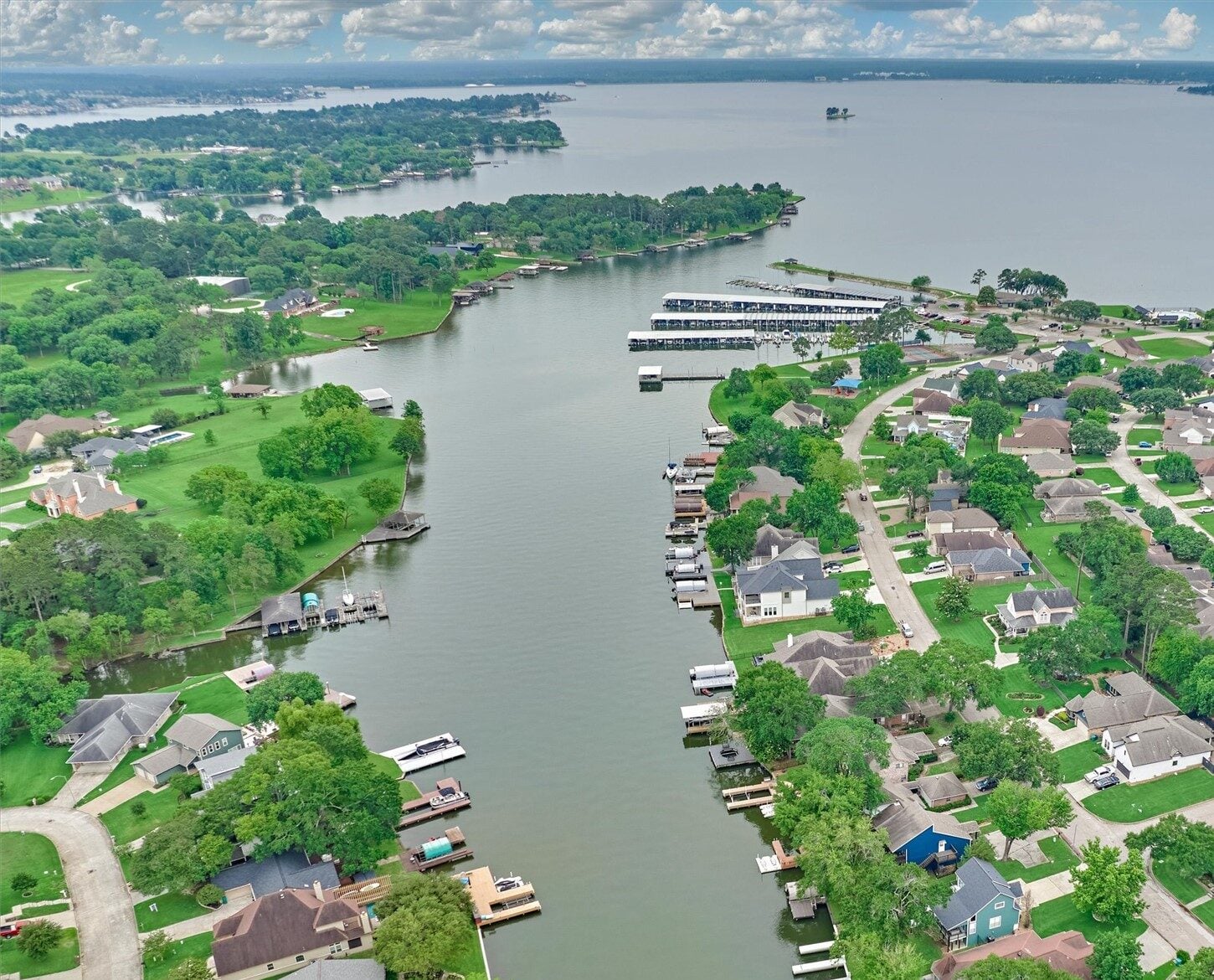 Real estate investment overview lake conroe guide 2026 | the mckellar group Aerial View of a Lakeside Residential Neighborhood with Tree lined Streets Houses and Docks Along a Winding Canal