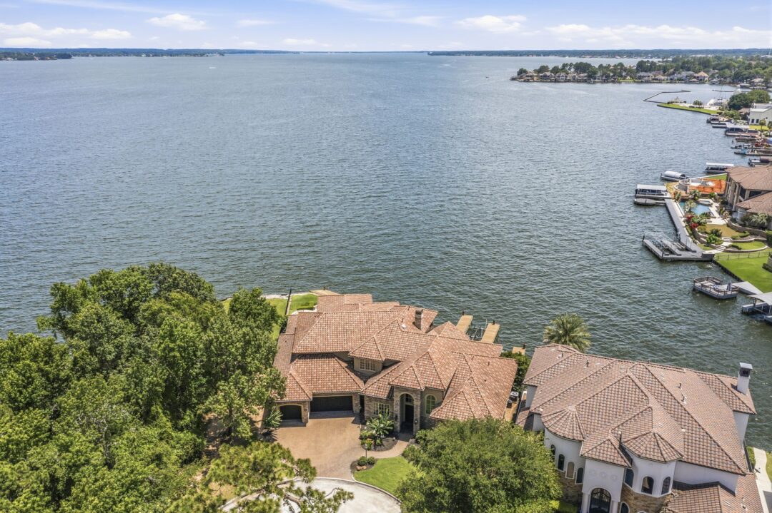 | the mckellar group Aerial View of a Large Mediterranean style House with Terracotta Roof Tiles Along a Waterfront Surrounded by Trees and a Neighboring Villa on the Shore