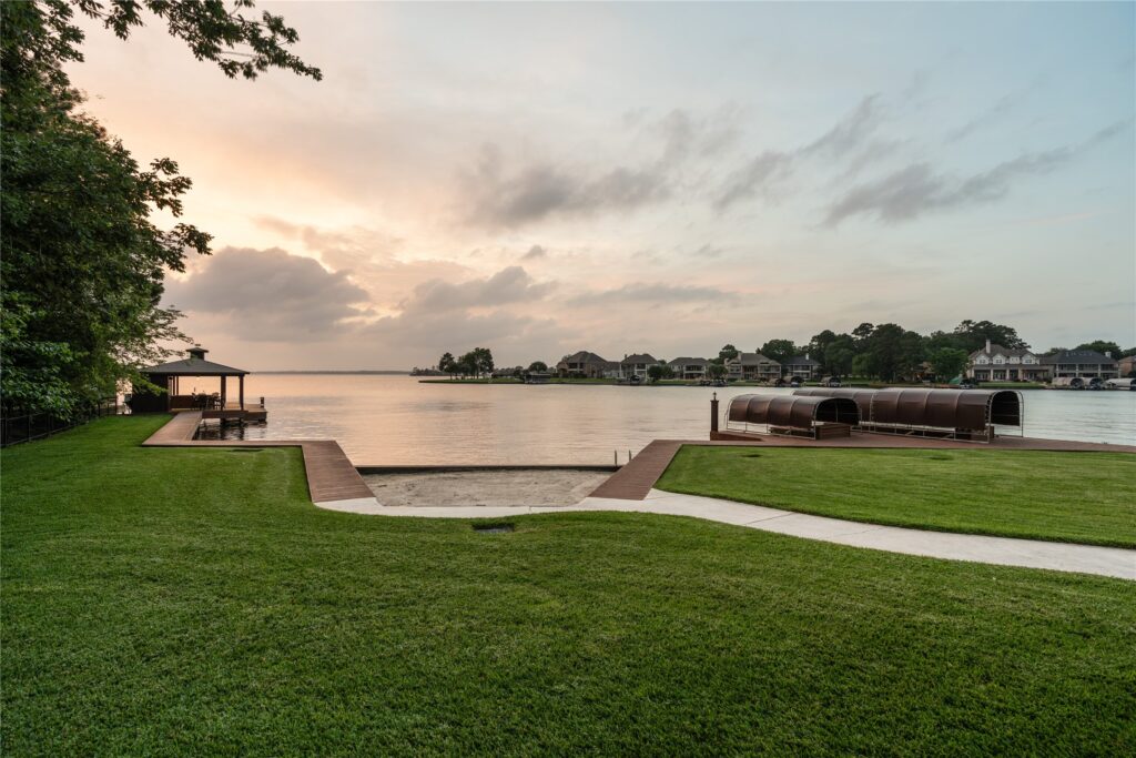 | the mckellar group Lakeside Residential Scene with a Manicured Green Lawn Wooden Walkways and a Gazebo over the Water at Sunset with Houses Lining the Opposite Shore