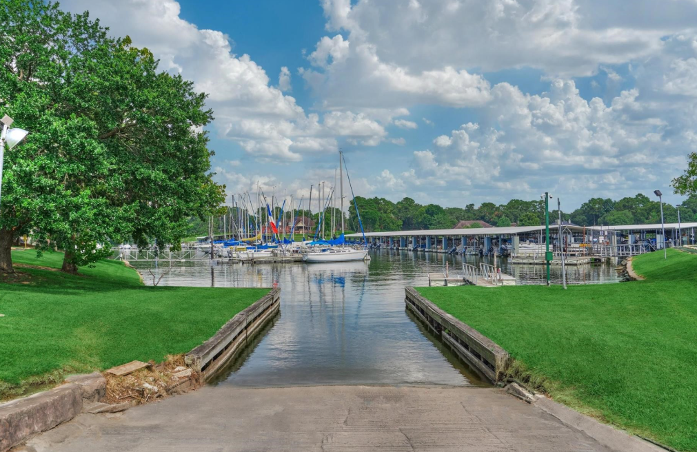 Marina with Sailboats Docked on Calm Water Green Lawn on Both Sides and a Blue Sky with Clouds