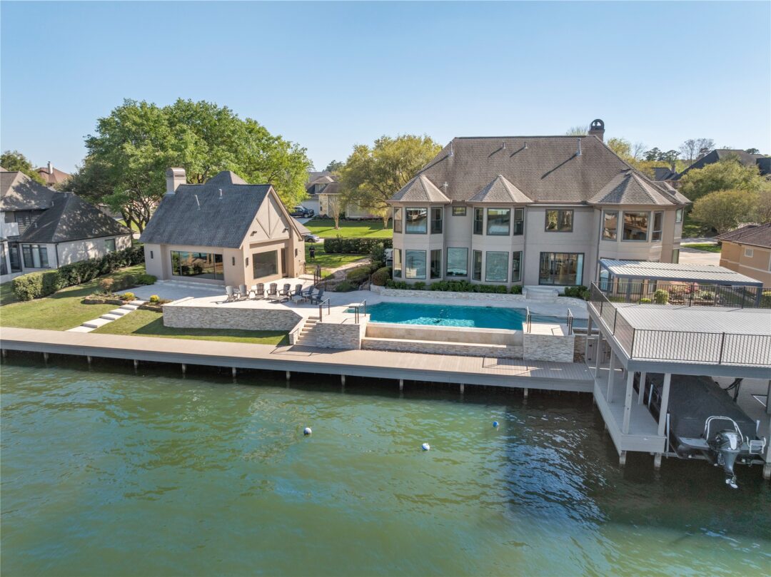 Aerial View of a Waterfront Suburban Neighborhood with Large Modern Homes a Rectangular Pool and a Wooden Dock Along a Canal