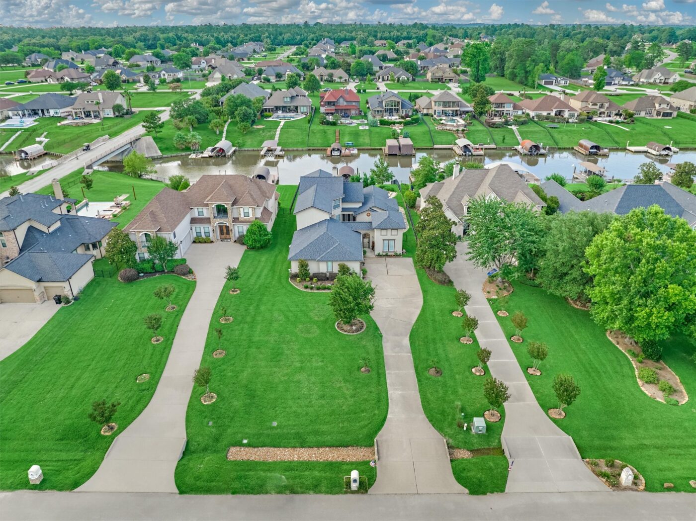 | the mckellar group Aerial View of a Suburban Neighborhood with Curved Driveways Manicured Lawns and a Canal with Boat Docks Behind the Houses
