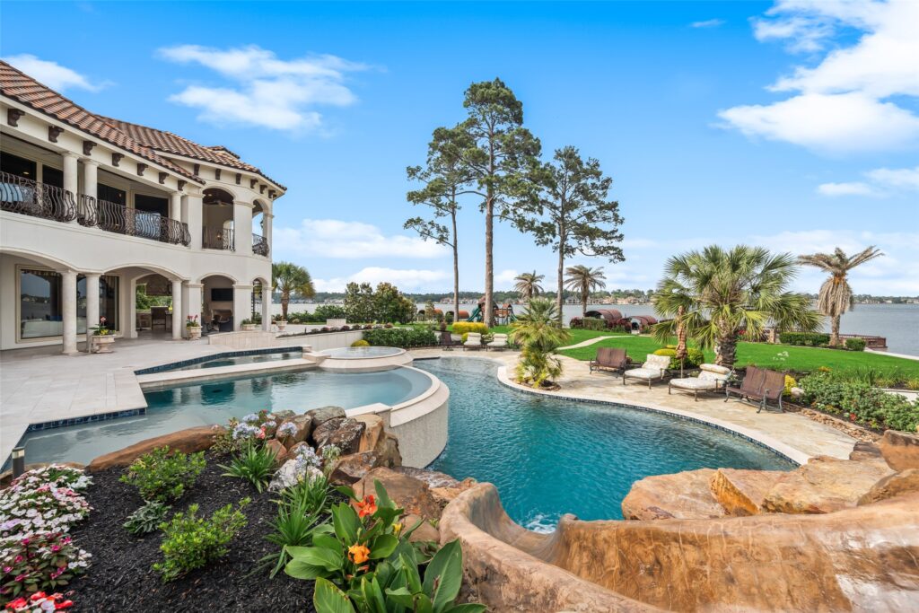 | the mckellar group Luxury Two story Villa with White Arches Tiled Roof and a Curved Pool in a Landscaped Backyard Overlooking a Lake
