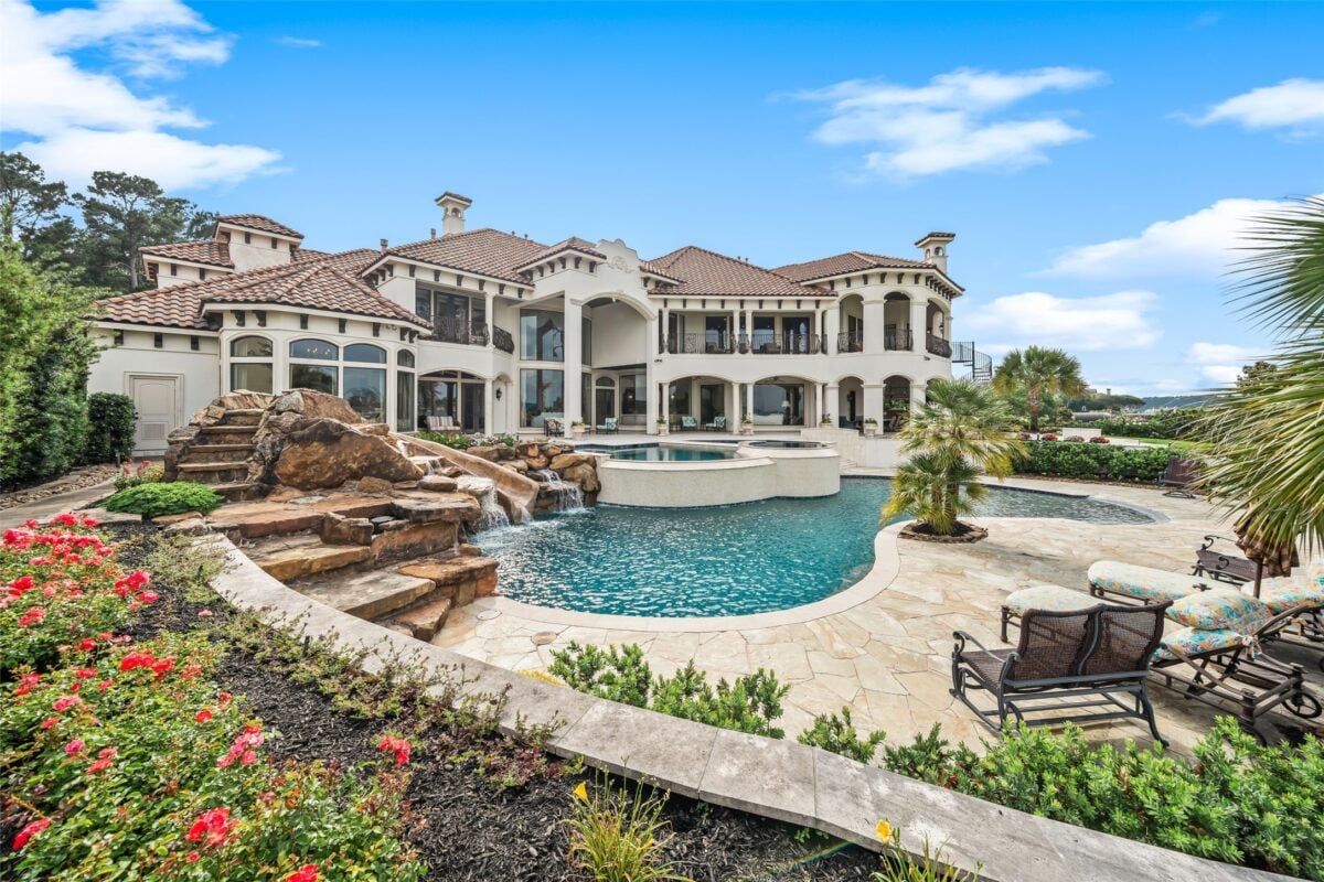 Enhancing your lake conroe property with water features | the mckellar group Luxurious White Villa with a Multi level Pool Rock Waterfall and Tropical Landscaping Under a Blue Sky